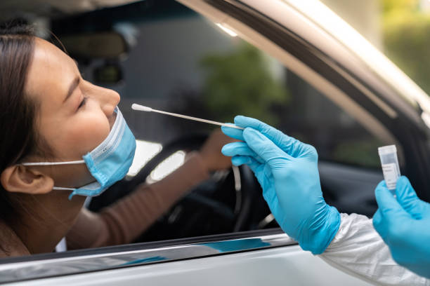 Asian woman Drive Thru COVID-19 testing with PPE medical staff Portrait of asian woman drive thru coronavirus covid-19 test by medical staff with PPE suit by nose swab. New normal healthcare drive thru service and medical concept. covid stock pictures, royalty-free photos & images