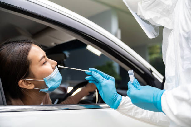 Asian woman Drive Thru COVID-19 testing with PPE medical staff stock photo