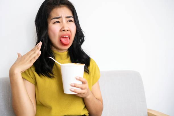 Asian woman eating very hot and spicy noodle from a cup her mouth and tongue burning and red Asian woman eating very hot and spicy noodle from a cup her mouth and tongue burning and red, unhealthy eating concept korean culture photos stock pictures, royalty-free photos & images