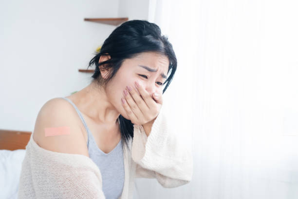 Asian woman feeling nausea and vomiting having allergic side effects after receiving the vaccine for covid-19 stock photo