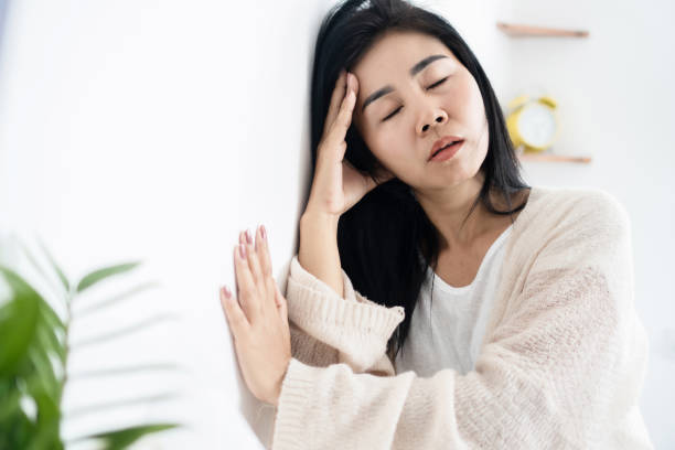 Asian woman having problem with Meniere's disease, fainting or dizziness hand holding her head stock photo