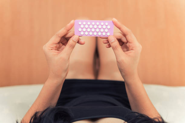 Asian woman holding contraceptive pills in the bed room, Health and medical concept stock photo