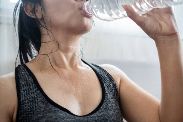Asian woman in sportwear drinking fresh water from bottle  after doing sport stock photo