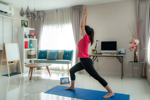 亞洲女性做瑜伽練習,遠離電腦,在家工作期間,通過數位平板電腦上的直播視頻課程進行午間鍛煉。 - 休息中 個照片及圖片檔