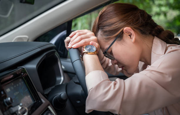 Asian woman napping in her car caused of tired from workload or feeling sleepy. stock photo