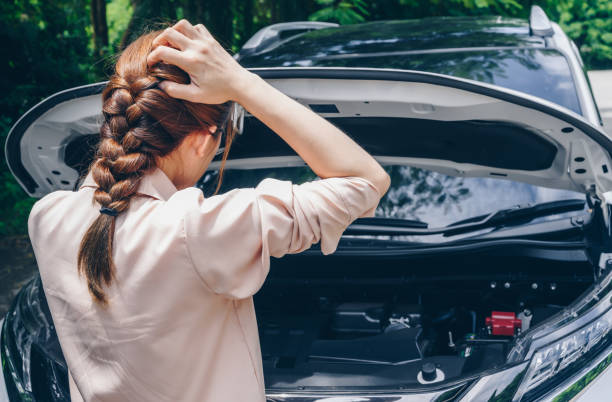Asian woman opened car hood for looking the problem of car breakdown while waiting for assistance on the road side. stock photo