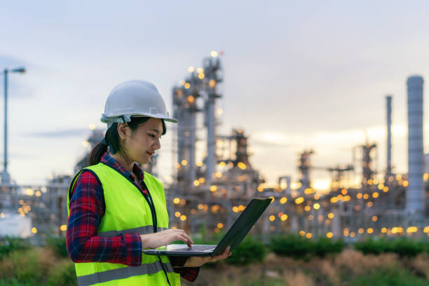 Asian woman petrochemical engineer working at night with notebook Inside oil and gas refinery plant industry factory at night for inspector safety quality control. Asian woman petrochemical engineer working at night with notebook Inside oil and gas refinery plant industry factory at night for inspector safety quality control. oil refinery factory stock pictures, royalty-free photos & images