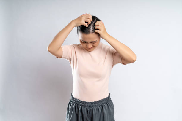 Asian woman scratching her head, standing isolated on white background. stock photo