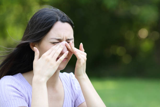 Asian woman scratching itchy eyes in a park stock photo