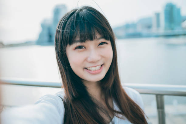 アジアの女性の笑顔は自分撮りを取る - 自撮り ストックフォトと画像