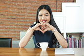 テーブルの上のコーヒーの前で微笑むアジアの女性
