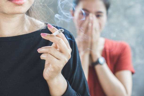 Asian woman smoking cigarette near people in family smelling pollution Asian woman smoking cigarette near people in family smelling pollution,passive smoking concept Smoking Kills stock pictures, royalty-free photos & images