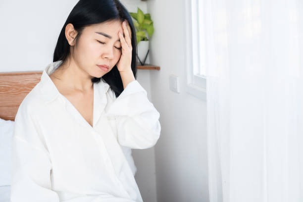 Asian woman suffering from headache, dizziness after wakeup in morning hand holding her head stock photo