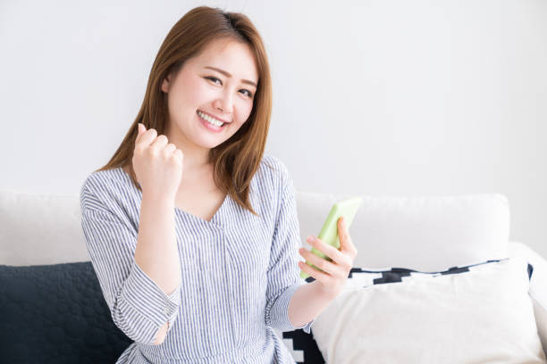 スマートフォンを見るためにアジアの女性 - 喜び ストックフォトと画像