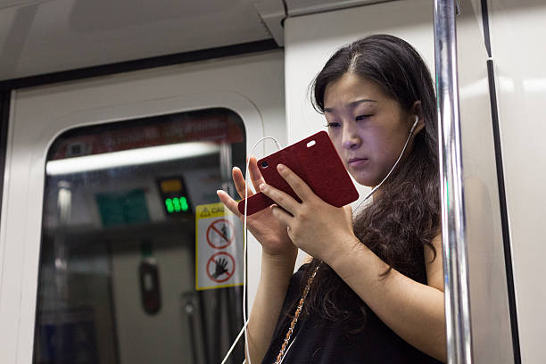 femme asiatique de taper sur smartphone dans le métro, singapour - smartphone car photos et images de collection