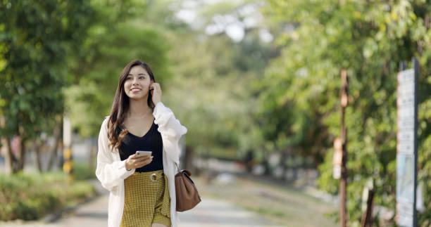 在城市街道上使用智慧手機的亞洲婦女圖像檔