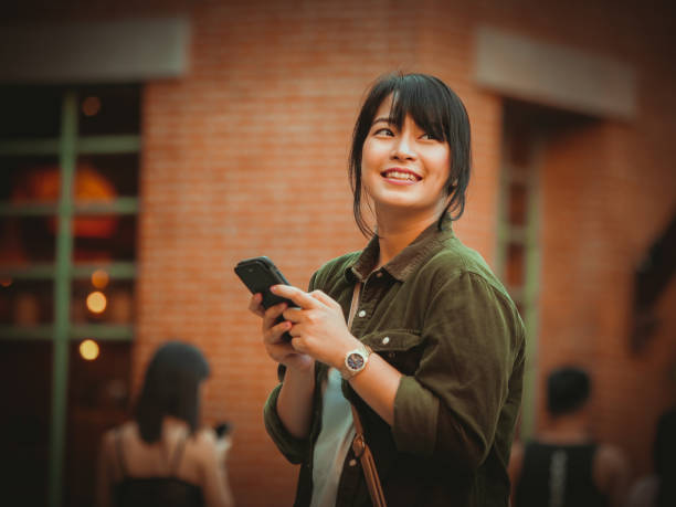 Asian woman using smartphone with happy mood smile face  in shopping mall stock photo