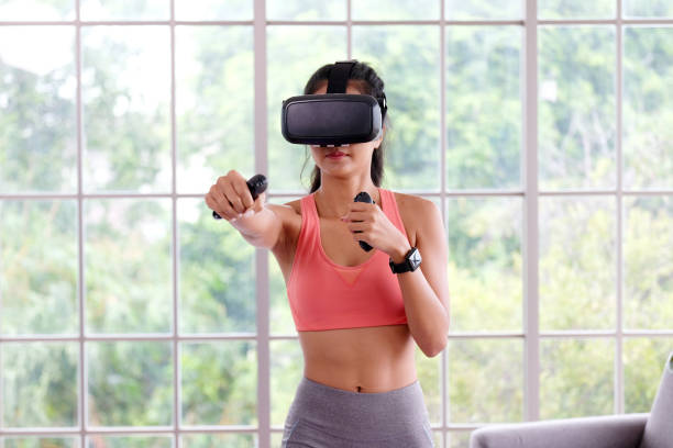 Asian woman virtual reality headset while exercise at home, Healthy asia girl wearing vr glasses for interactive exercise, e sport, Female and wearable technology stock photo