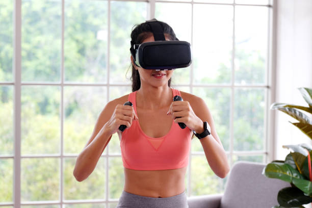Asian woman virtual reality headset while exercise at home, Healthy asia girl wearing vr glasses for interactive exercise, e sport, Female and wearable technology stock photo