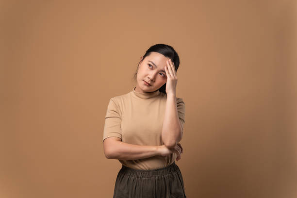 Asian woman was sick with headache standing isolated on beige background. stock photo
