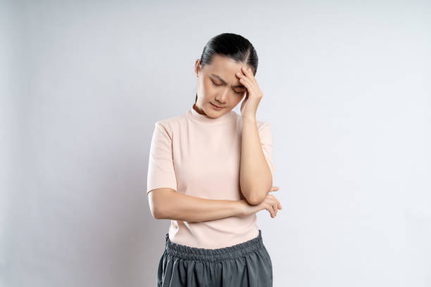 Asian woman was sick with headache standing isolated on white background. stock photo