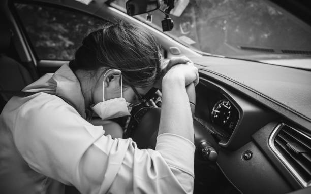 Asian woman wearing mask, napping in her car caused of tired from workload or feeling sleepy. stock photo