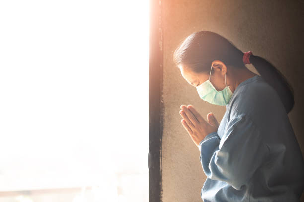 Asian woman wearing medical mask and praying stock photo