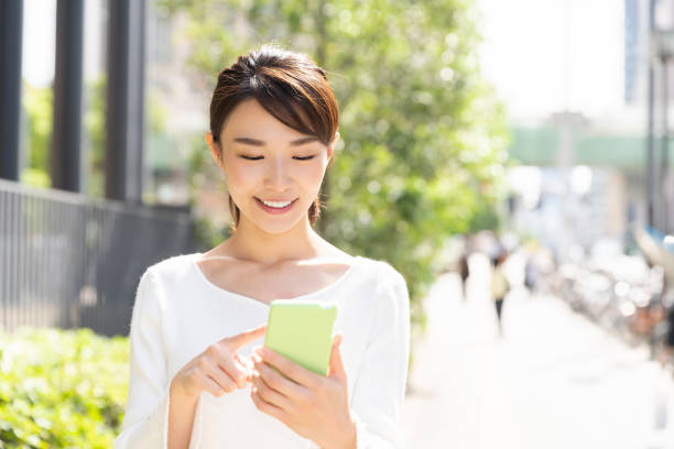 スマートフォンを見るアジアの女性 - スマホ　女性　日本人 ストックフォトと画像