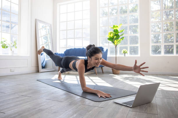 Asian women learn yoga online in video conferencing, Fitness Instructor, Yoga online, Video call on laptop. stock photo