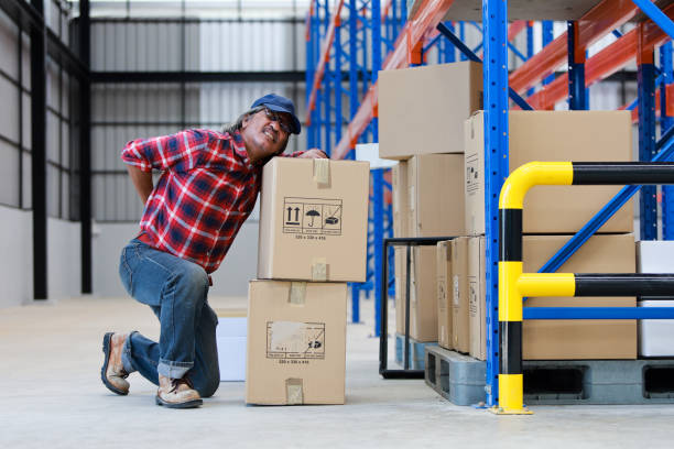 Asian worker man hurt his back "nlift heavy box in factory stock photo