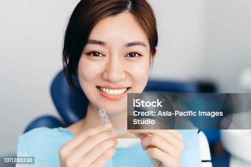 istock Asian young attractive woman holding orthodontic retainers in dental clinic. Invisalign orthodontics concept. 1311280330