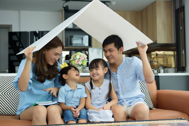 Asian young family happy to playing housing, Mother with Father and Children at living room in new home. New life family, Stable housing concept. Soft focus on Children center. stock photo