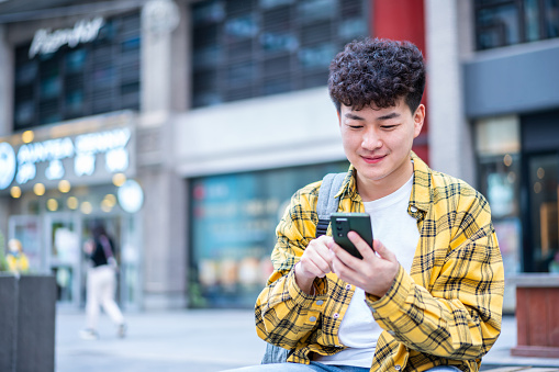 Asian young handsome man using smart phone in city street