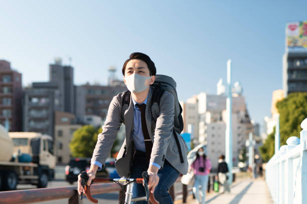 自転車で通勤するカジュアルな服装でアジアの若者 - 通勤 ストックフォトと画像