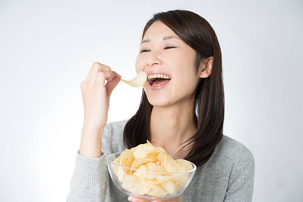 Asian young woman eating potato chips stock photo
