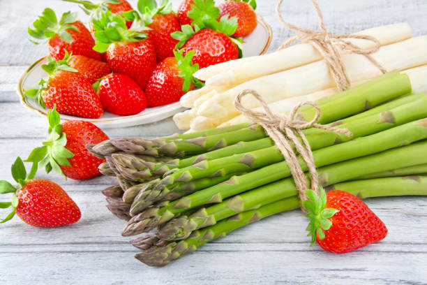 Asparagus and strawberries against wooden background stock photo
