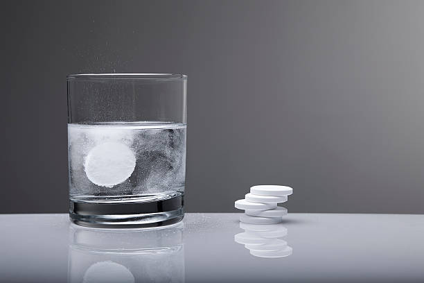 aspirin paracetamol pill splashing into glass of water - pijnstiller stockfoto's en -beelden