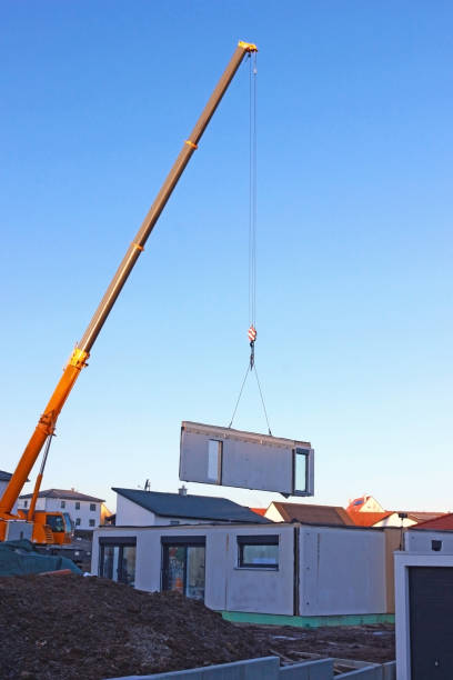assembly of a prefabricated house assembly of a prefabricated house, crane lifting a wall component with doors up in the air prefabricated building stock pictures, royalty-free photos & images