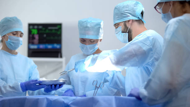 Assistant giving surgeon sterile medical equipment, invasive hospital operation Assistant giving surgeon sterile medical equipment, invasive hospital operation surgery stock pictures, royalty-free photos & images