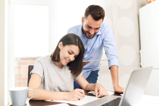 Assisting girlfriend with taxes Content confident young man using tablet app while assisting girlfriend with taxes, young woman filing document filing documents stock pictures, royalty-free photos & images