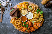 assorted beer snacks. Onion rings, chicken wings, french fries, and sauses