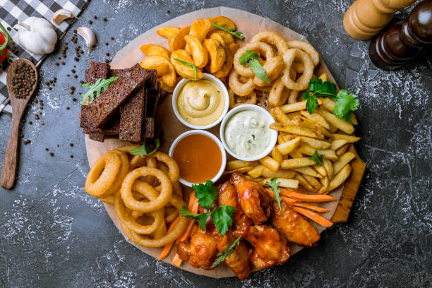 assorted beer snacks assorted beer snacks. Onion rings, chicken wings, french fries, and sauses appetizer stock pictures, royalty-free photos & images