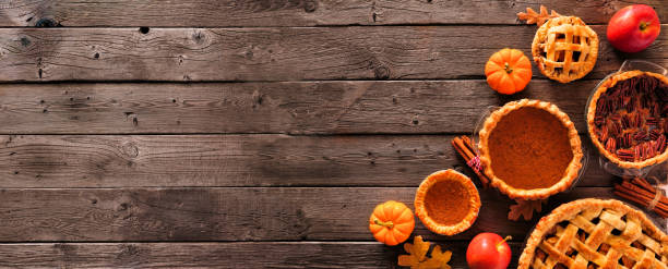 Assorted homemade autumn pies. Pumpkin, apple and pecan. Corner border on a rustic wood banner background. Assorted homemade autumn pies. Pumpkin, apple and pecan. Overhead view corner border on a rustic wood banner background with copy space. thanksgiving holiday stock pictures, royalty-free photos & images