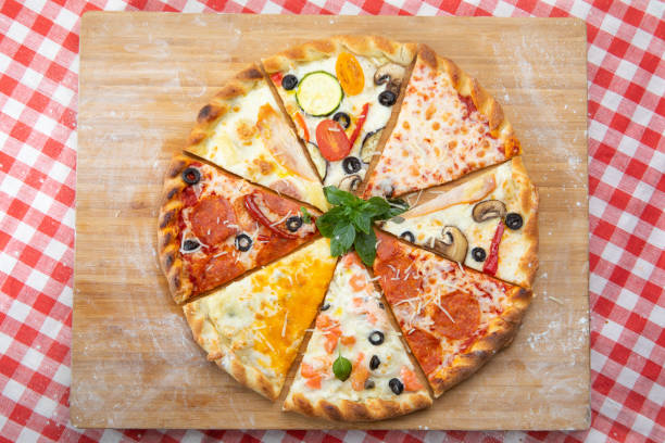 diverse bitar av pizza närbild med olika ingredienser dekorerade med basilika - pork pine bildbanksfoton och bilder