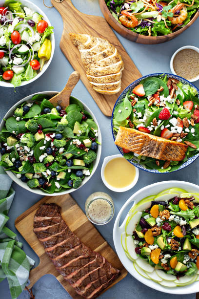 Assorted salads on the table Assorted salads with fresh ingredients on the table with grilled steak, chicken brest and salmon, clean eating concept healthy dinner stock pictures, royalty-free photos & images