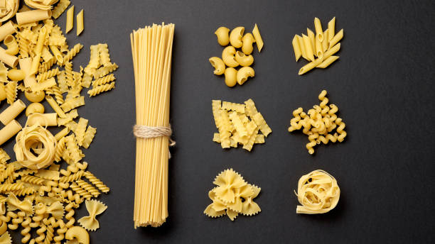 Assorted types of pasta on black background. Top view. Various forms of pasta.  uncooked pasta stock pictures, royalty-free photos & images