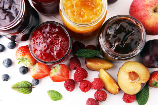 assortment of jams, seasonal berries, plums, mint and fruits stock photo