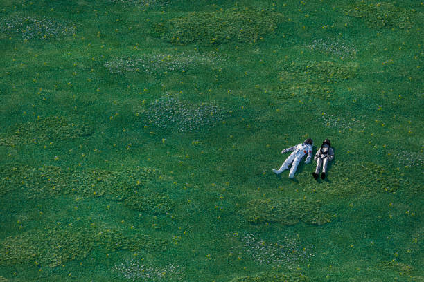 astronauts lying in the meadow - astronauta green imagens e fotografias de stock