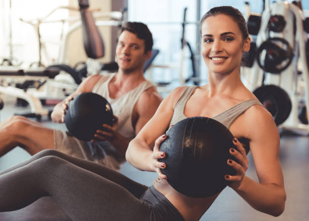 At the gym Attractive young muscular man and woman are working out with balls in gym yoga ball work stock pictures, royalty-free photos & images