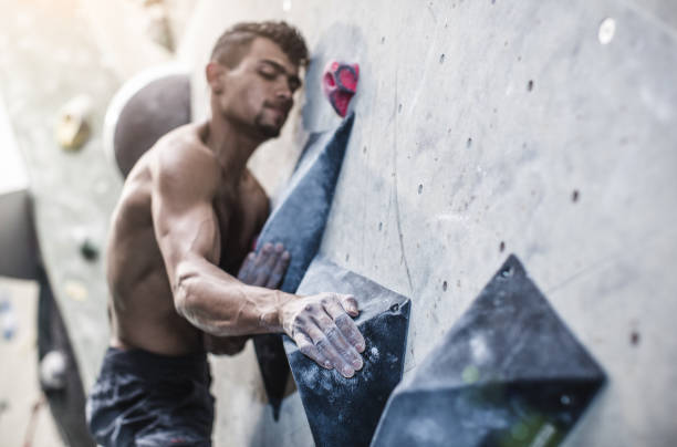 Athlete Climbing in a Bouldering Gym Athlete Climbing in a Bouldering Gym bouldering stock pictures, royalty-free photos & images
